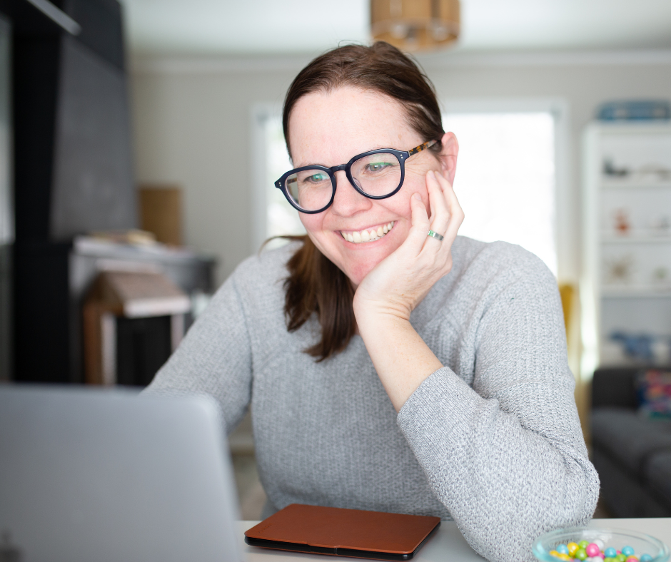 Mujer emprendedora, con lentes, mirando su laptop sonriendo. Foto tamaño vertical