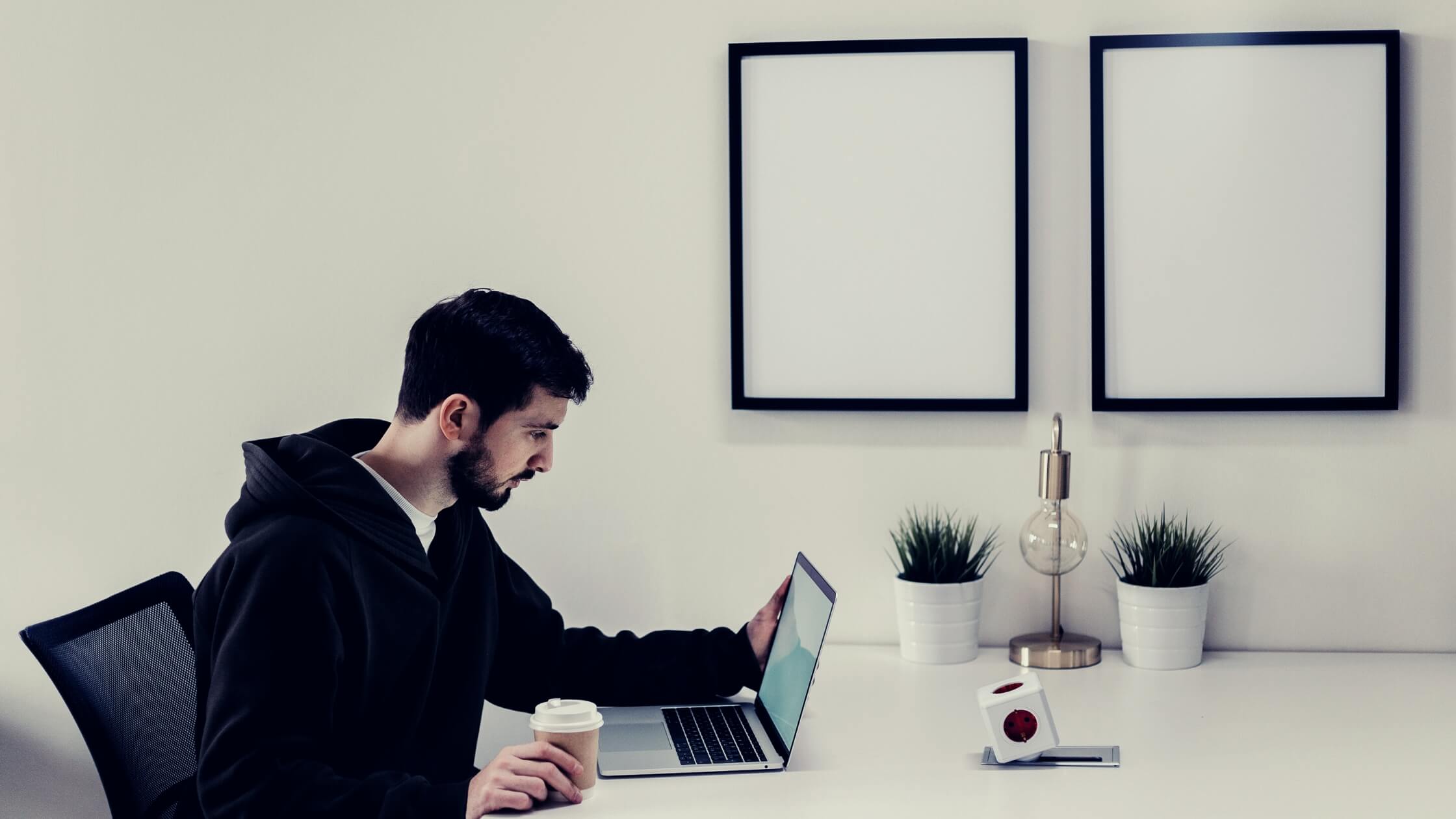 Hombre freelancer con sweater, trabajando con su laptop en su oficina