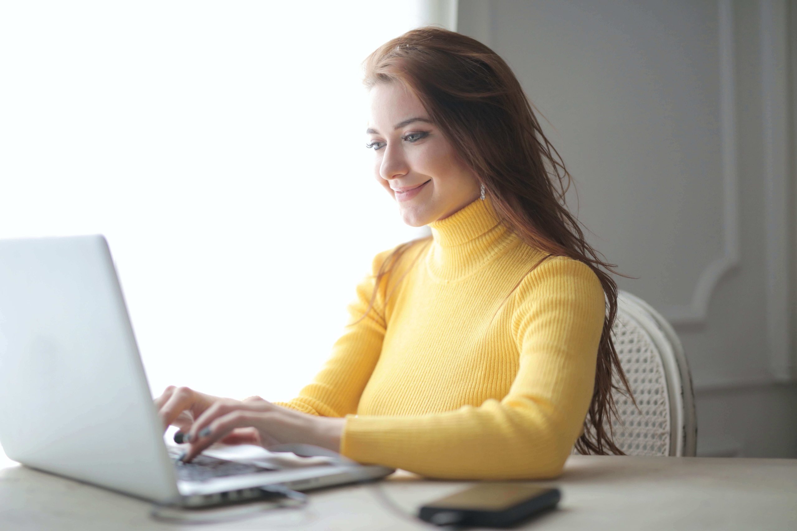 Mujer asistente virtual sonriente frente a su laptop