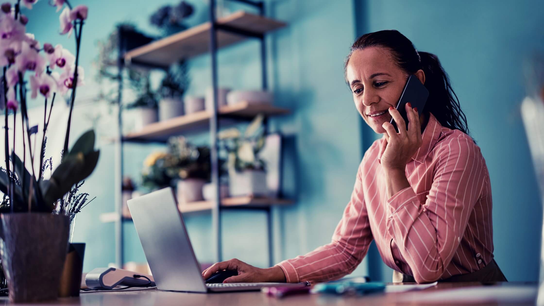 Mujer hablando por teléfono y viendo su laptop