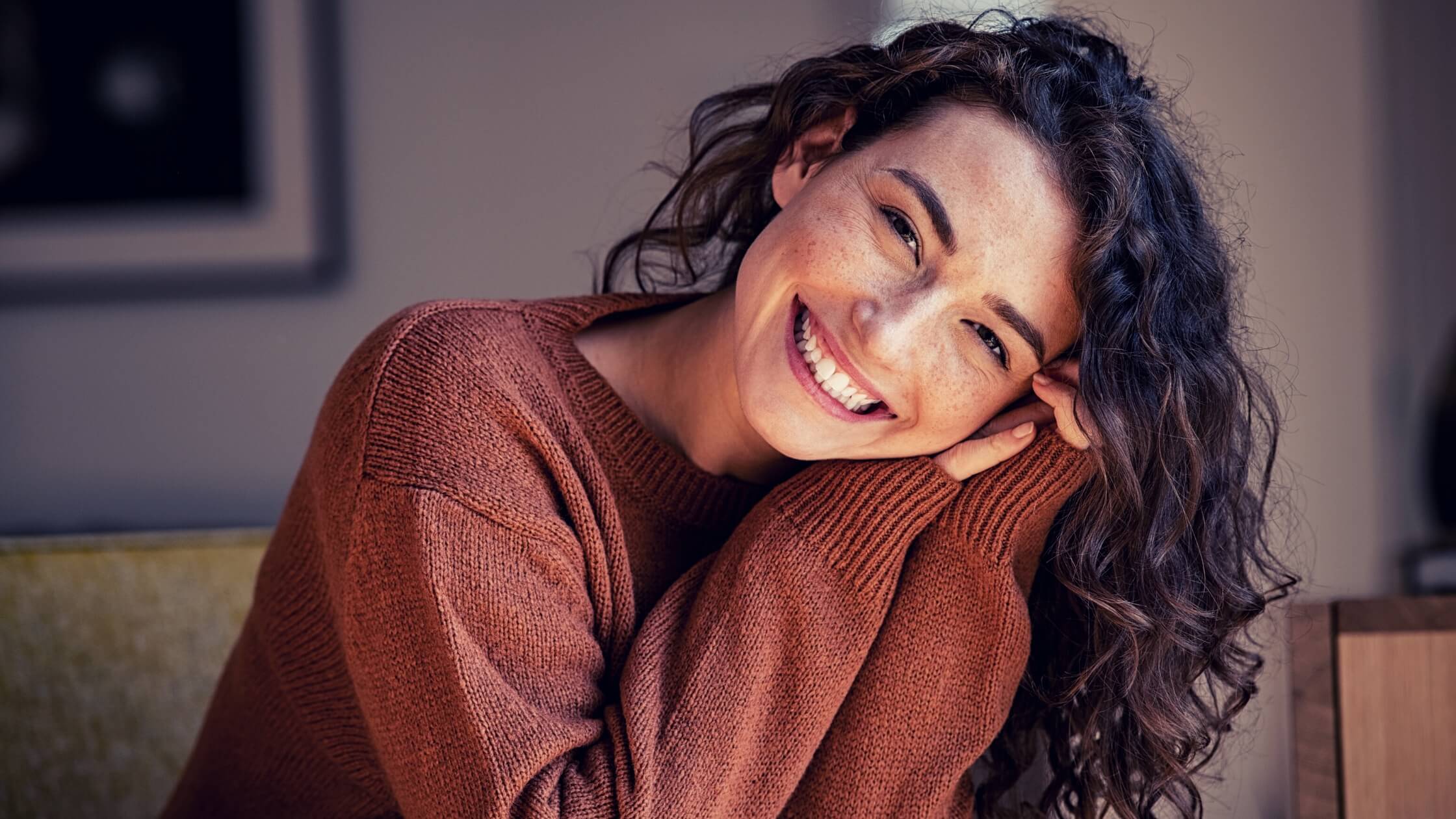 Mujer de unos 35 años sonriendo, con un sweater color marrón.