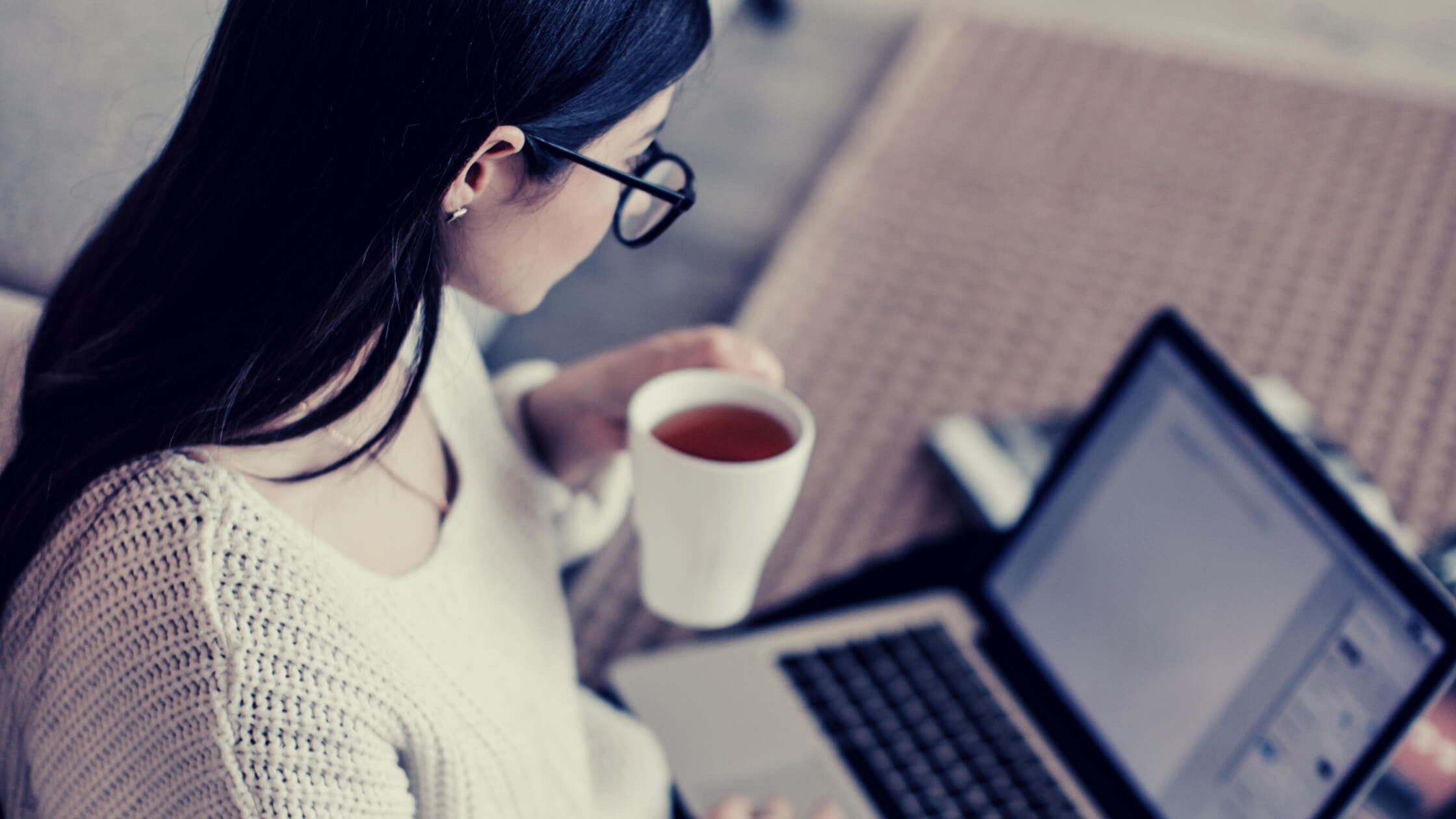 Mujer emprendedora tomando café mientras trabaja en su computadora